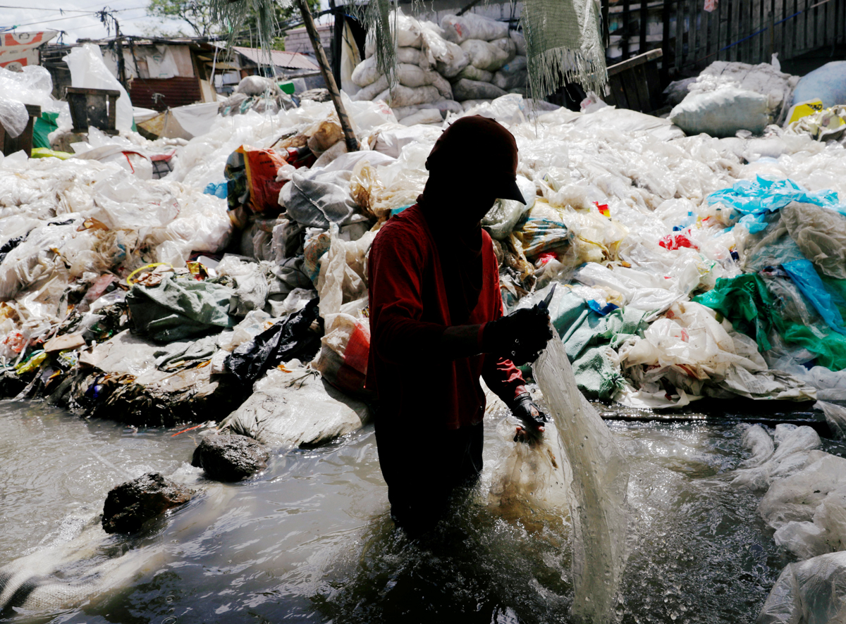 Aman washes plastic for recycling in a murky pond at Payatas district, Quezon City, Metro Manila, Philippines. [Dondi Tawatao/Reuters]