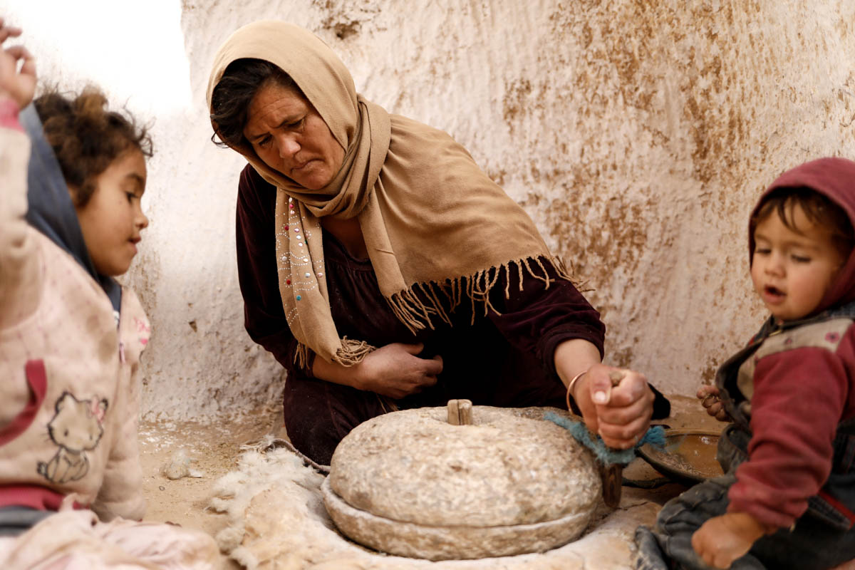 Saliha Mohamedi, 36, grinds wheat at her troglodyte house. [Zohra Bensemra/Reuters]
