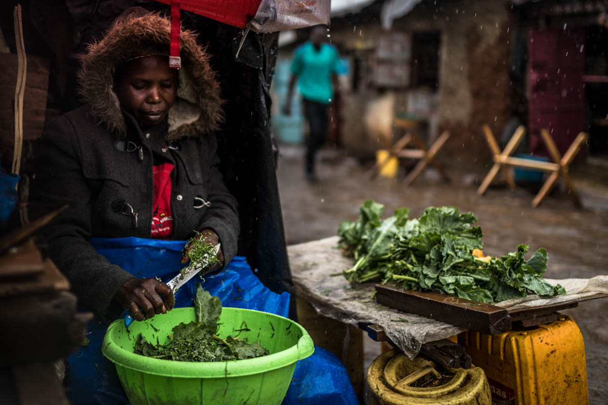 Phenice, a grocery and vegetable vendor in the Gatwekera village of Kibera, cannot afford to close her stall when it rains, as her family depends on her business for survival. With the arrival of heavy rains, preparing, displaying and storing products and food becomes a constant challenge for the female vendors. [Natalia Jidovanu/Al Jazeera]