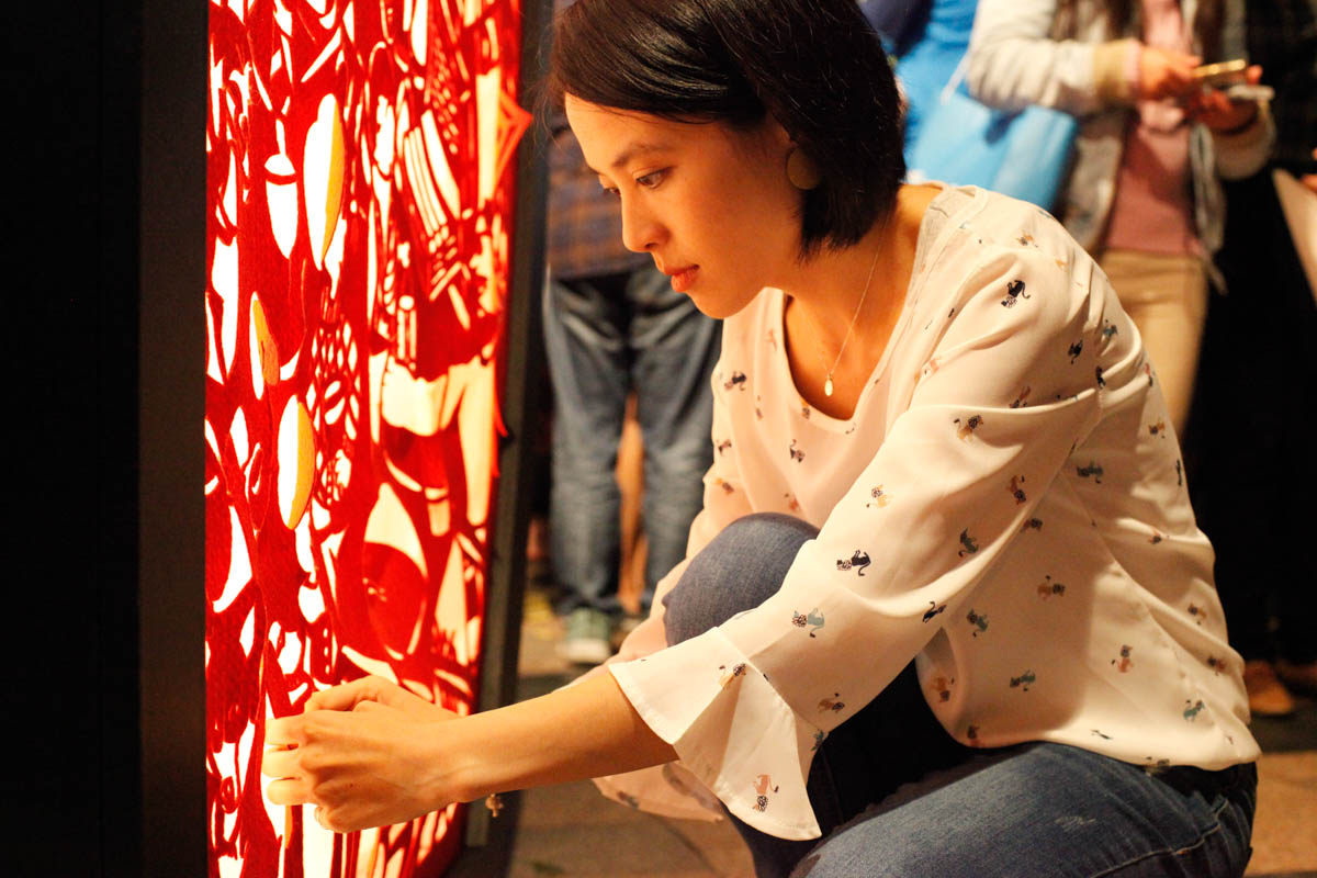 Paper-carvingartist Johan Cheng uses needle and strings to fix her cloth carving installation that was damaged by the crowd. The lantern-shaped, tunnel-like installation 'Back To The Times That We Hold Hand Lanterns' was made by Cheng and her seven students as felons in Taipei Prison. 'In a class where I asked them to carve anything on paper while imaging having their last month in life, everyone carved pictures relating with their family,' Cheng said. Having grown up in Taipei and having sweet memories of lantern festivals and carnivals with her grandmother, she contributed her two works to Taipei Lantern Festival for the first time. [Yunjie Liao/Al Jazeera]