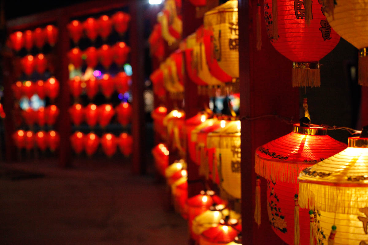 "Fortuneand honour come with blooming flowers" is written on bucket-sized lanterns hanging on the walls. Traditional lanterns are commonly seen in special zones for temples and shrines that participate in the fairs and carnivals. [Yunjie Liao/Al Jazeera]