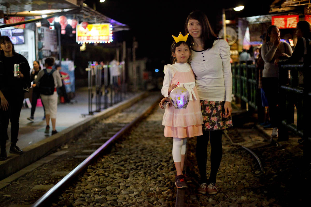Afterreading a story about sky lanterns, eight-year-old Uni You asked her parents to visit Ping Xi. It is also the first day of her new school semester. She dresses up and travels with her parents from Yilan to Shi Fen by train. Her parents help her choose a small hand lantern to walk with. They chose the LED lantern with 'Shi Fen' printed on it. [Yunjie Liao/Al Jazeera]