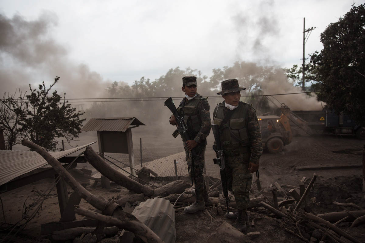 Soldiers stand guard outside a destroyed home in the disaster zone covered in volcanic ash. [Rodrigo Abd/AP Photo]