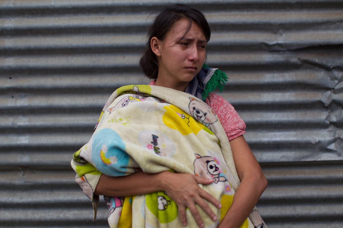 Kimberly Sofia Gonzalez cries as she holds a baby during the burial of her brother-in-law Erick Rivas, 20, who died in the hospital after suffering burns from the eruption of the Volcan de Fuego. Rivas was returning home from the town of San Miguel Los Lotes after visiting his girlfriend, who survived. [Luis Soto/AP Photo]