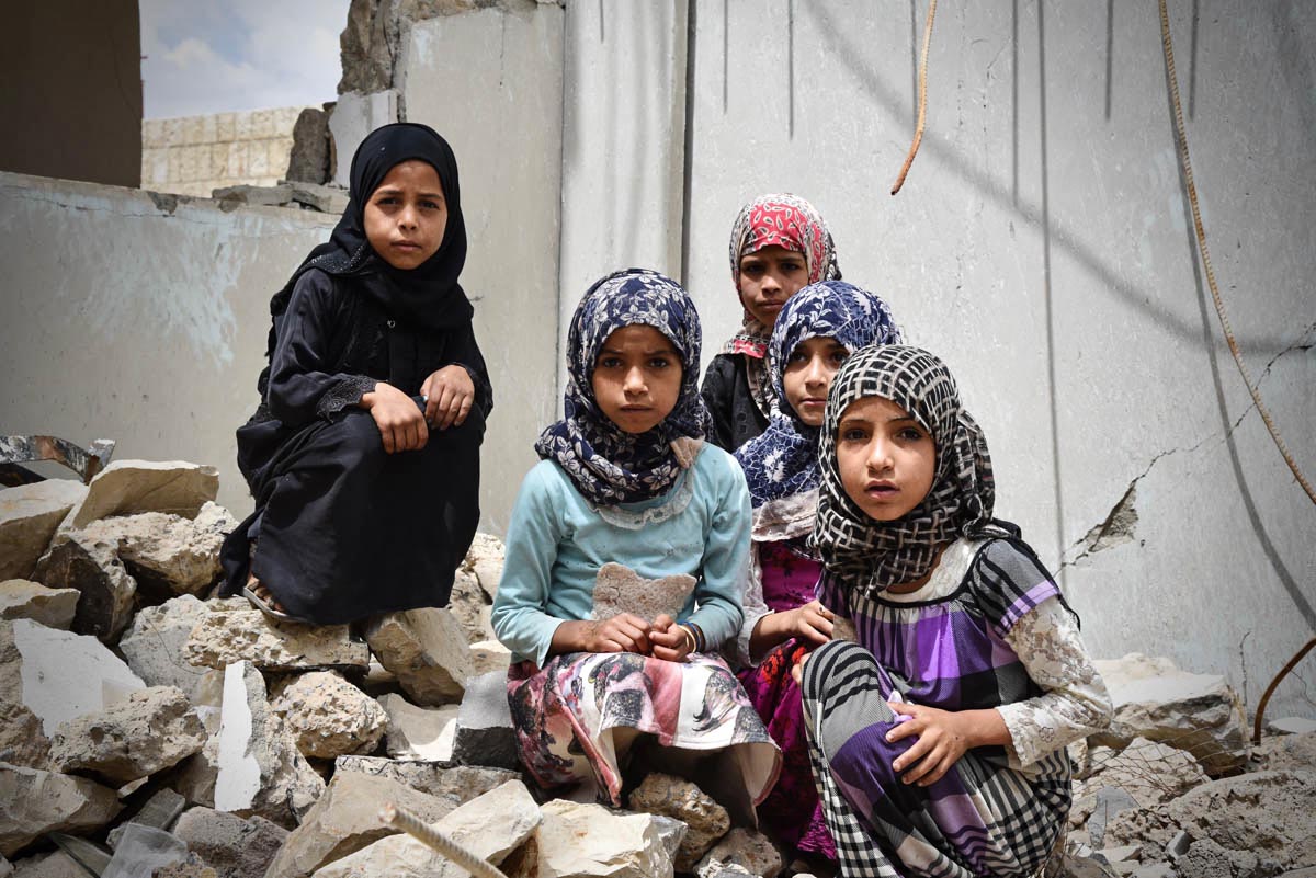 A group of young girls sits in the rubble of their school in Amran city. The school had been open for only a year before it was struck by an air attack in 2017. Two thousand children were left without education as a result. [Suze van Meegen/Norwegian Refugee Council]