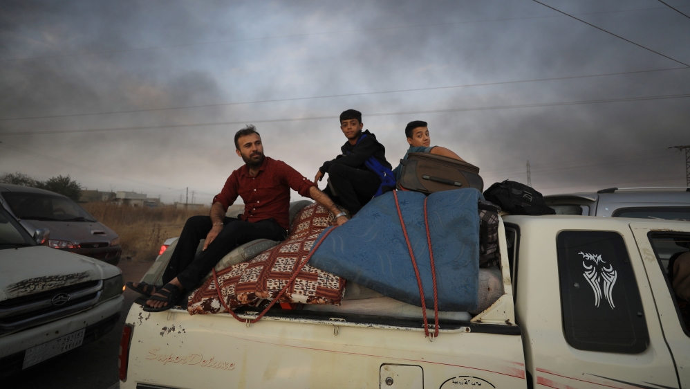 People sit on belongings at a back of a truck as they flee Ras al Ain town, Syria October 9, 2019