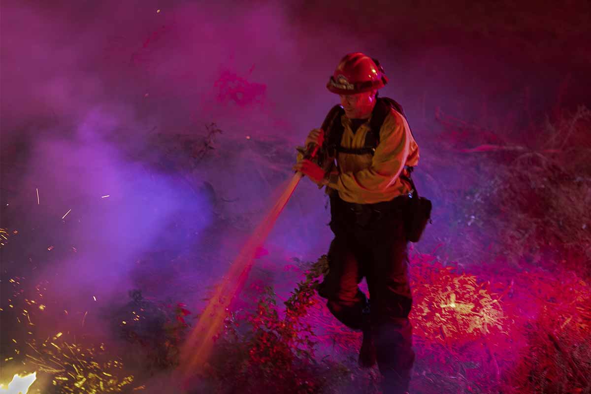 Zjarrfikësit që merren me një zjarr në Kaliforni.  Shteti i Shteteve të Bashkuara u godit nga një seri zjarresh të rrezikshme dhe me lëvizje të shpejtë në fillim të këtij muaji pasi erërat e Santa Ana u krijuan me shpërthime të forta deri në 130 km (81 milje) në orë dhe lagështi jashtëzakonisht të ulët.  [David McNew / AFP]