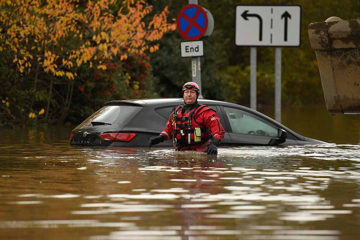 Një anëtar i shërbimit të zjarrit dhe shpëtimit endet përmes ujërave të përmbytjes në Rotherham, në Anglinë veriore.  Një shi me vlerë mbi një muaj ra në pjesë të Anglisë në vetëm një periudhë 24-orëshe.  [Oli Scarff / AFP]