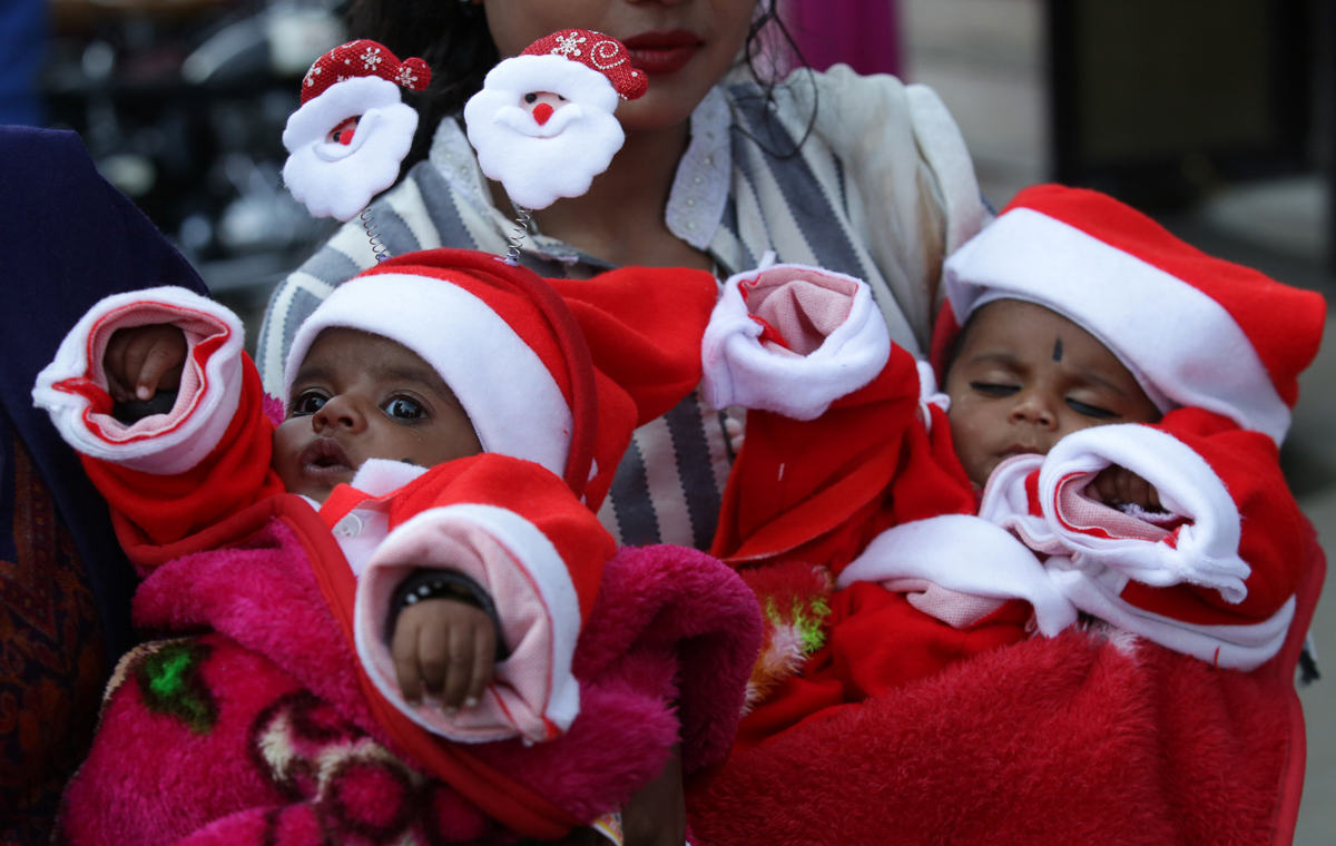 Indian women carry babies dressed as Santa Claus as they take part in a Christmas procession in Jammu, India, 21 December 2019. Christians in India comprise a little over 2 percent of the population. [Jaipal Singh/EPA]