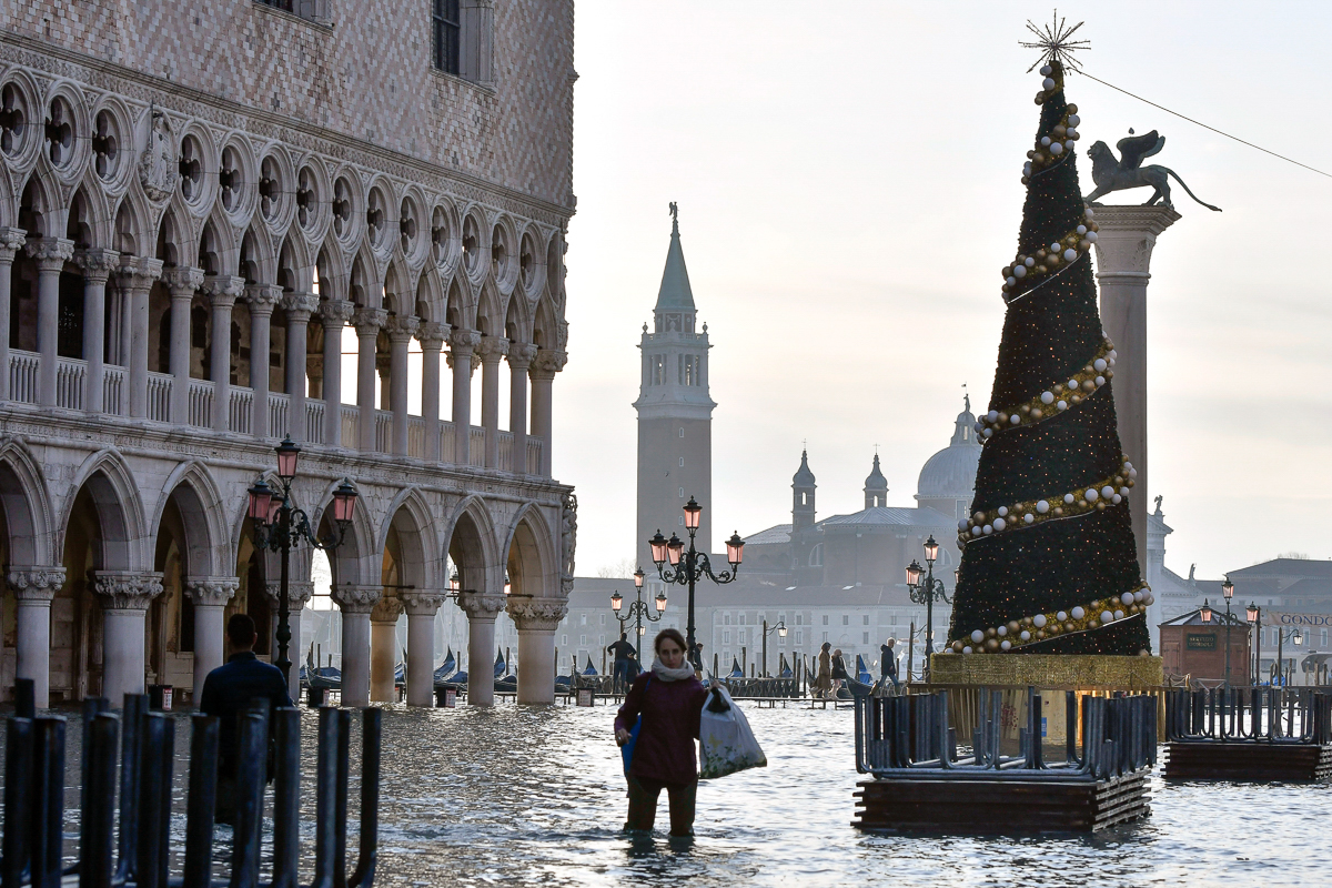 A woman wades through high water during a high tide of 1.44 metres (4.72 feet), in St Mark's Square, Venice, Italy. [Luigi Costantini/AP Photo]