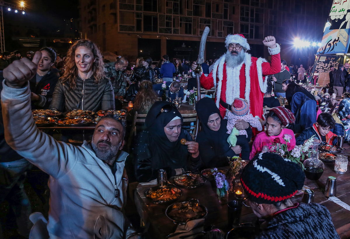 A protester dressed as Santa Claus greets diners during a charity Christmas dinner in Martyrs' square in central Beirut, Lebanon. [Nabil Mounzer/EPA]