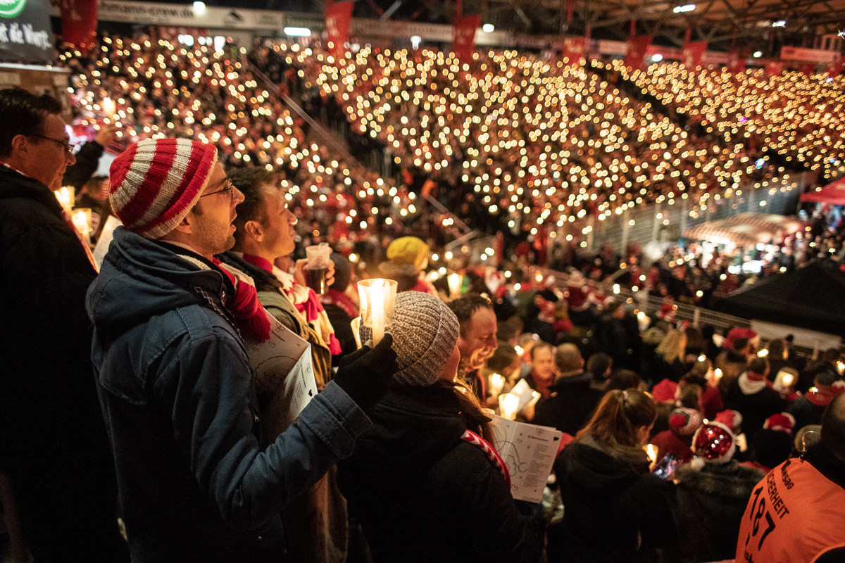 Fans of FC Union Berlin sing Christmas carols as they hold candles in Berlin, Germany, 23 December 2019. [Omer Messinger/EPA]