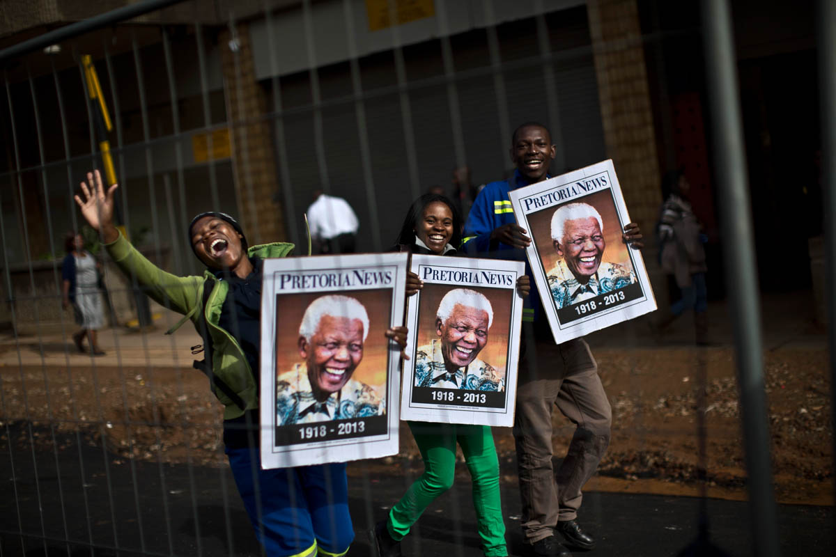 South African mourners hold posters of late former President Nelson Mandela and chant as the convoy transporting his body passes by, in Pretoria, South Africa, on December 11, 2013. Mandela died on December 5 at 95. [Muhammed Muheisen/AP Photo]