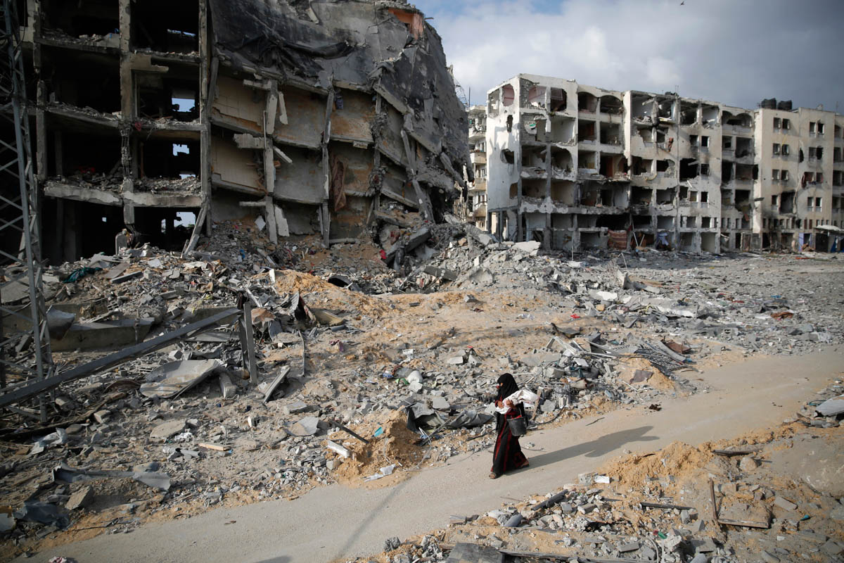 A Palestinian woman walks past buildings destroyed by what police said were Israeli air attacks and shelling in the town of Beit Lahiya in the northern Gaza Strip August 3, 2014.  [Finbarr O'Reilly/Reuters]