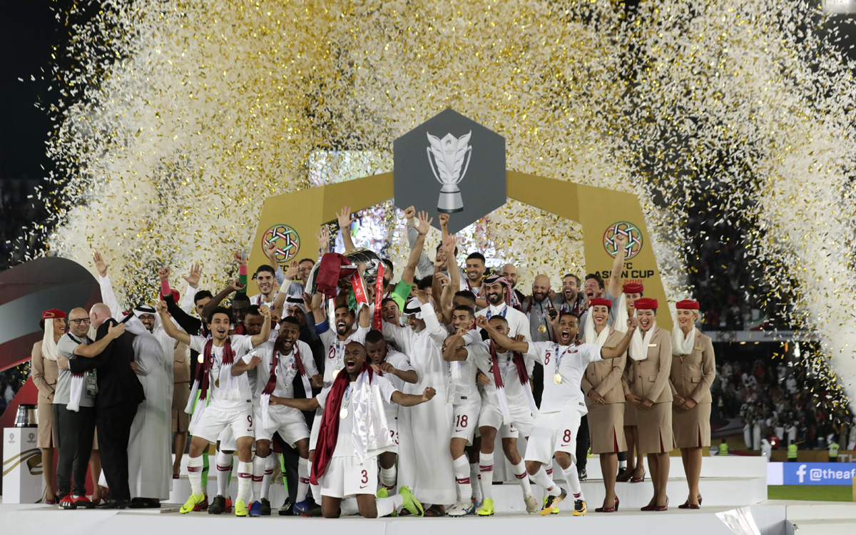 Qatar's Hasan al-Haydos raises the trophy as the team celebrates its first major football victory. [Suhaib Salem/Reuters]