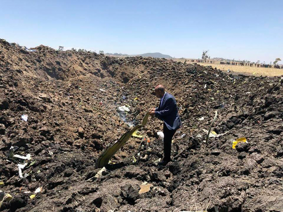 The CEO of Ethiopian Airlines, Tewolde GebreMariam, in a crater at the crash site, examines wreckage of the plane that crashed shortly after takeoff from Addis Ababa. [Facebook via AP]