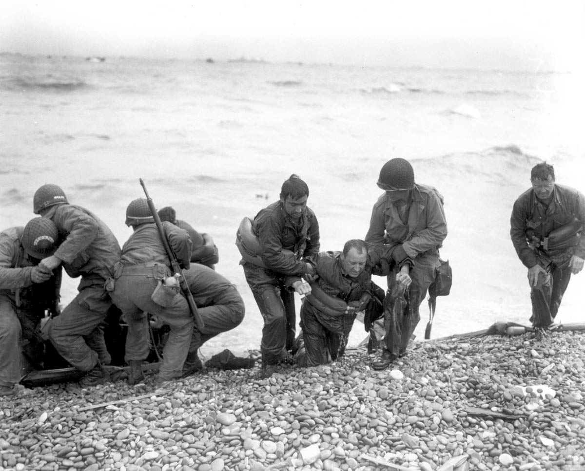 Members of an American landing party assist troops whose landing craft was sunk by enemy fire off Omaha Beach, near Colleville-sur-Mer, France June 6, 1944. [Weintraub/US National Archives/Reuters]