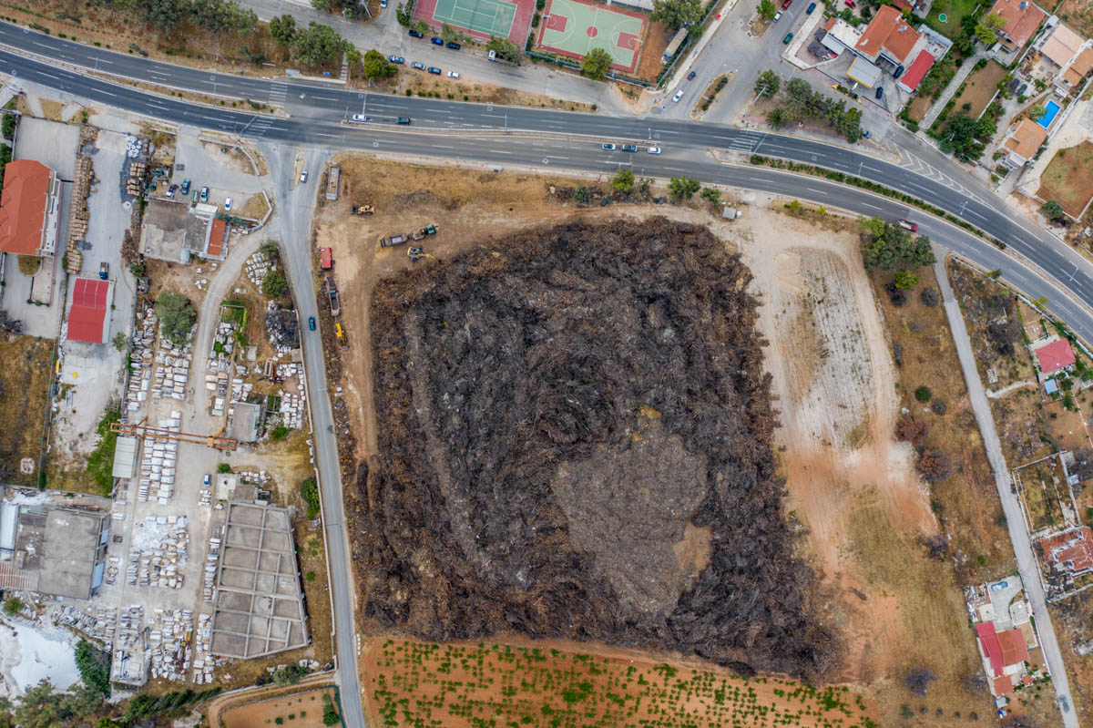 Locals say the clean-up operation is months behind schedule and warn that a plot of land in the area containing a bulky mass of burned branches and trunks is a time bomb for a new fire. [Dimitris Sideridis/Al Jazeera]