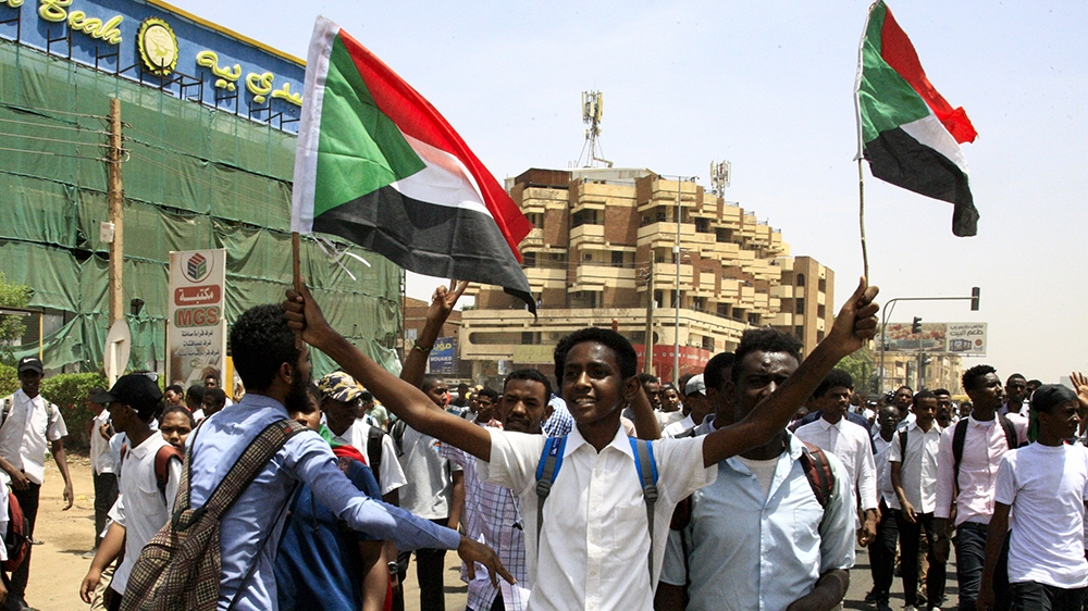 Sudanese students wave national flags as they protest in the capital Khartoum on July 30, 2019, a day after teenagers were shot at a rally against shortages of bread and fuel in the town of al-Obeid, 