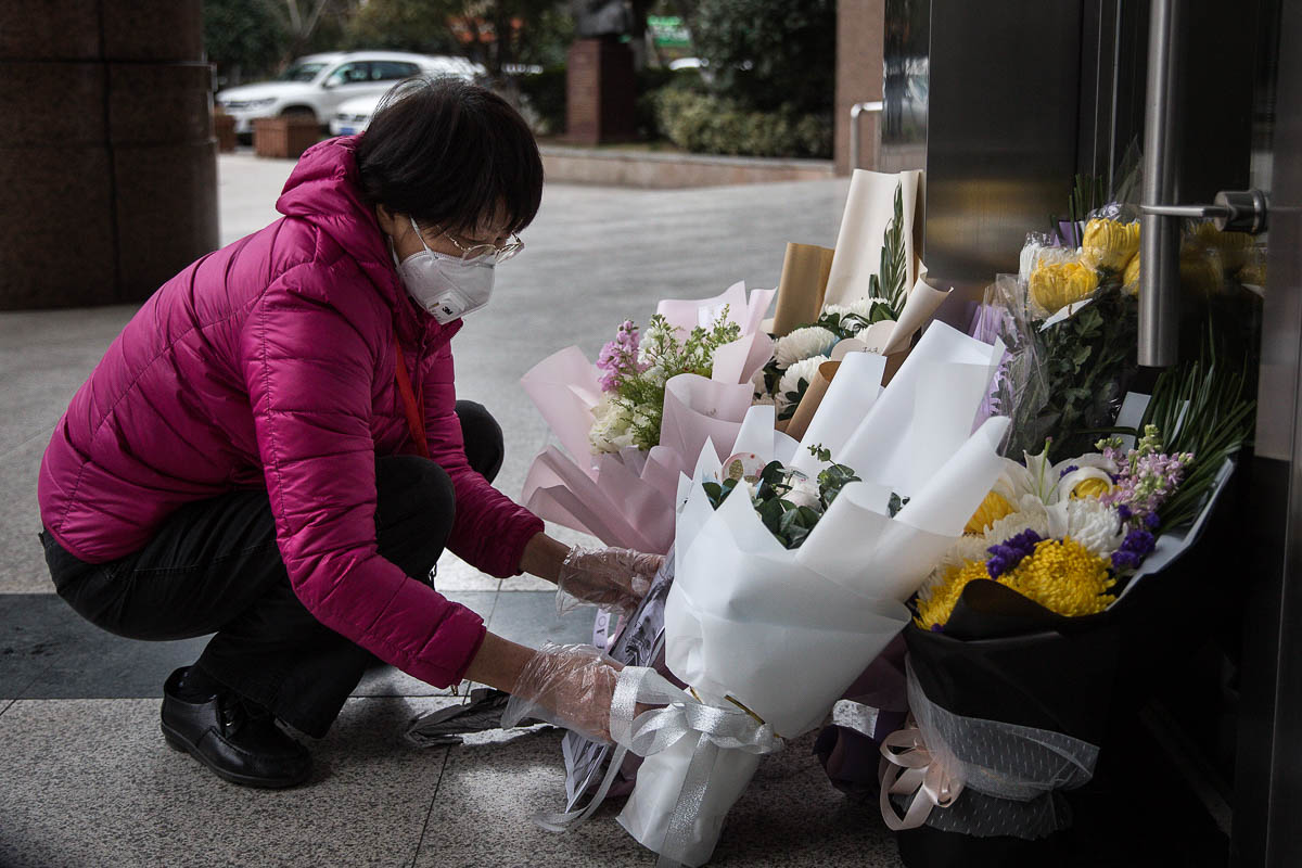 A resident lays flowers in tribute to Dr Li Wenliang at the hospital where he worked. Li, who died of the disease and has been hailed as a national hero, was reprimanded by officials after warning about the virus in December. [Getty Images]
