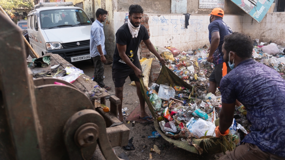 Workers sort through the garbage to remove pieces of glass or concrete which is not allowed to be put in the garbage truck [Shone Satheesh Babu/Al Jazeera]