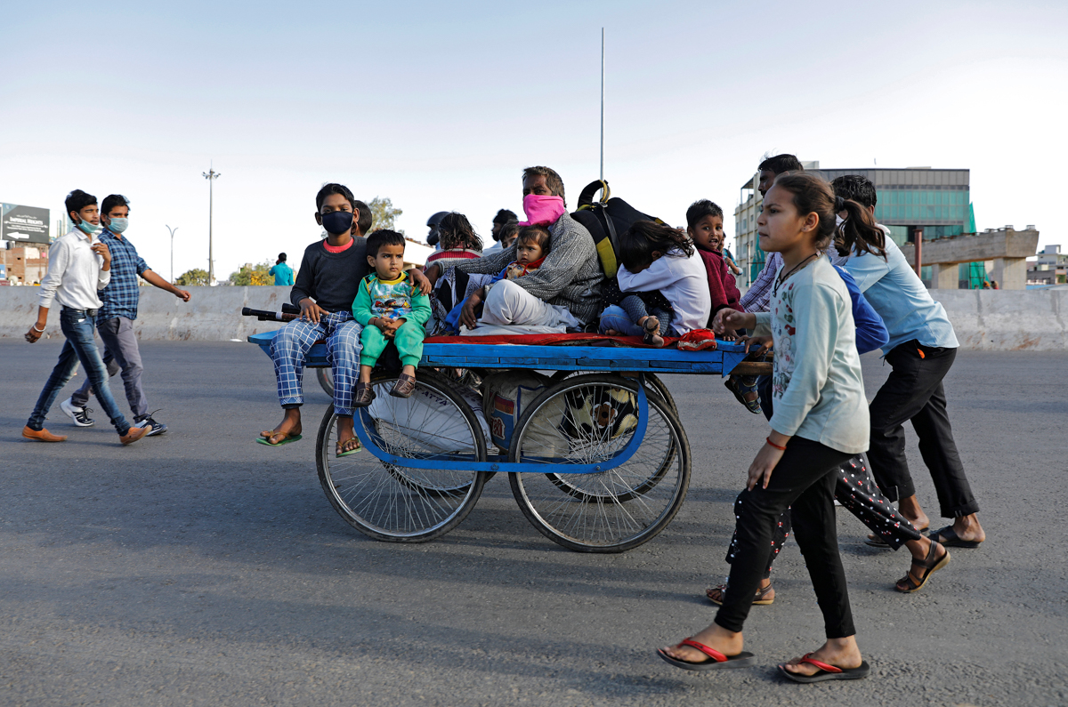 A migrant worker rides a cart with his family on a highway as they return to their villages, during the 21-day nationwide lockdown. [Adnan Abidi/Reuters]