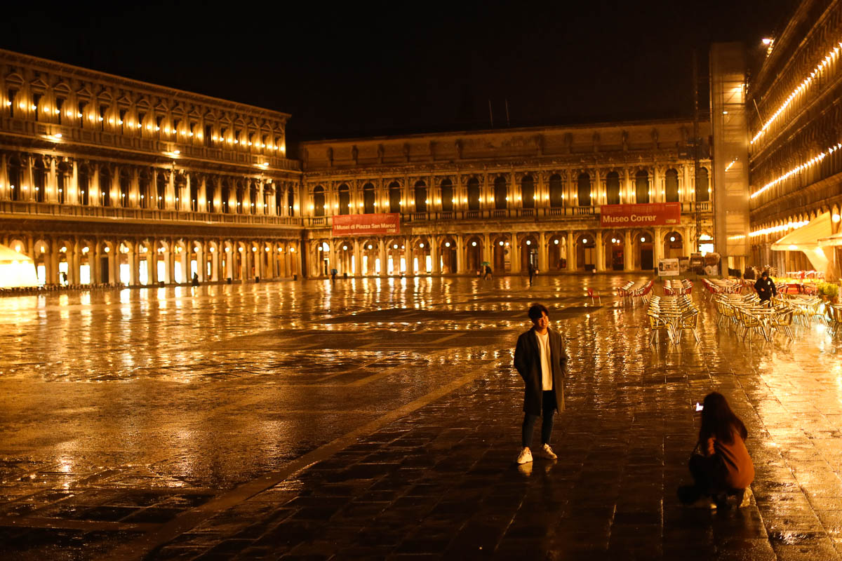 Tourists take photographs in an empty St Mark's Square during a rainy day in Venice, on March 2. [Francisco Seco/AP Photo]