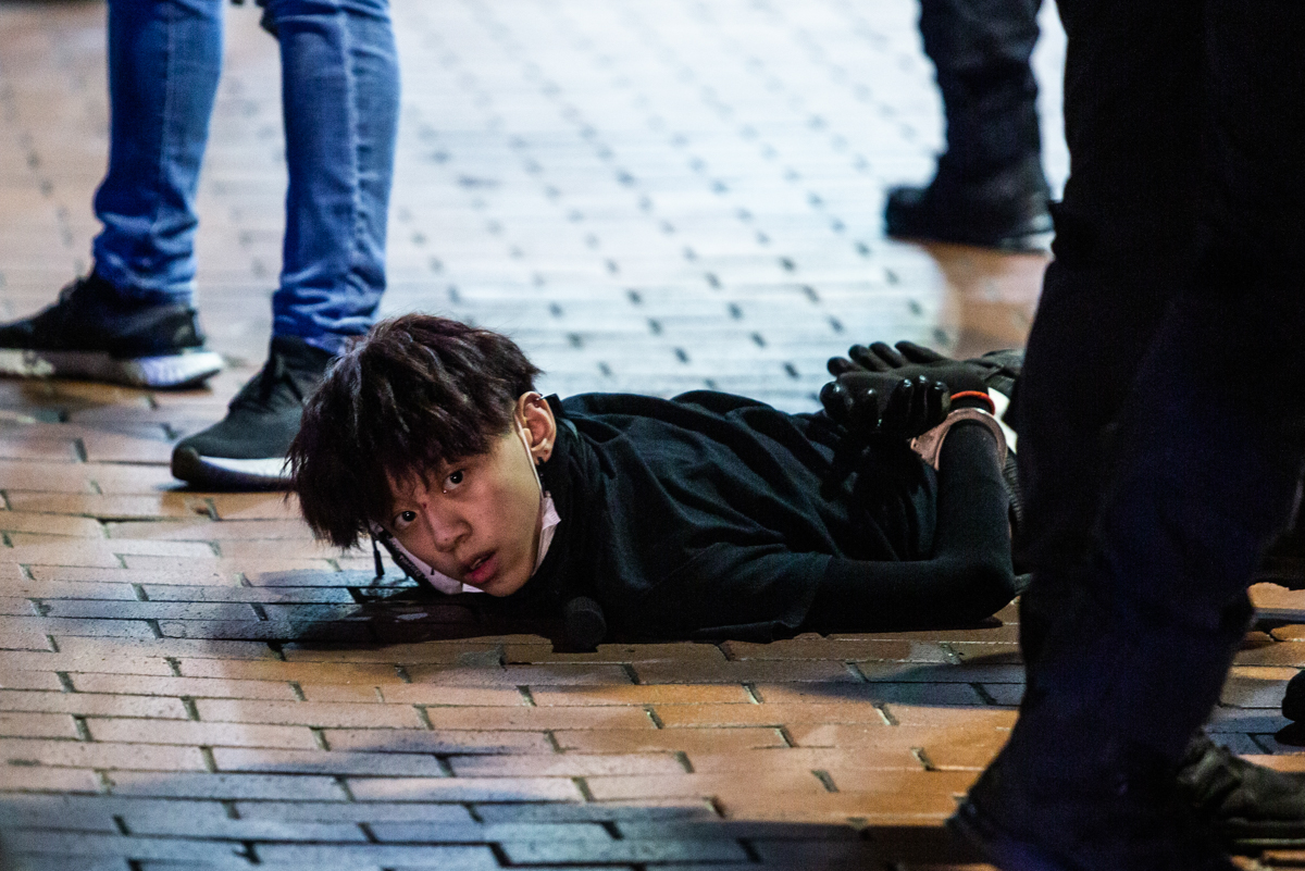 Undercover police arrest and handcuff a pro-democracy demonstrator in Mong Kok district. At least three arrests were made while groups of officers conducted multiple stop-and-searches. [Isaac Lawrence/AFP]