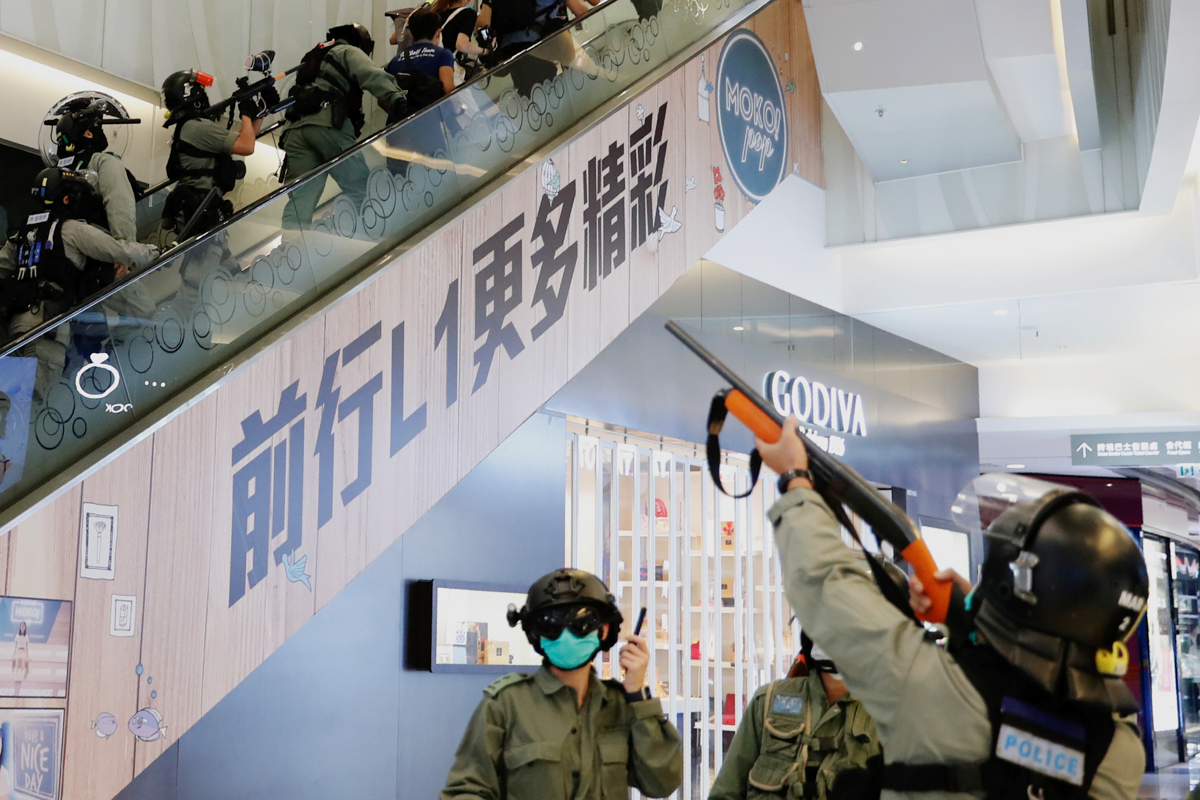 Riot police fire pepper spray projectile inside a shopping mall as they disperse anti-government protesters. [Tyrone Siu/Reuters]