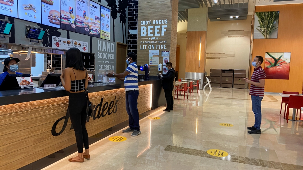 People wearing protective face masks order food as they keep social distancing at the food court in Dubai mall after the UAE government eased a curfew and allowed stores to open