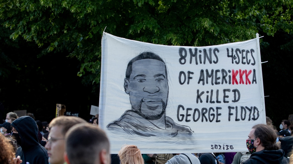 Participants in a rally against the violent death of African-American George Floyd by a white policeman hold a poster in front of the US Embassy with the words 