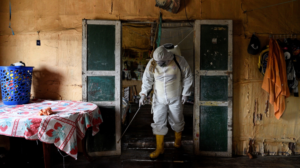 A local volunteer, who is helping to disinfect buildings in his town during the coronavirus disease (COVID-19) outbreak, wears protective clothing as he disinfects a home with a chlorine solution, in 