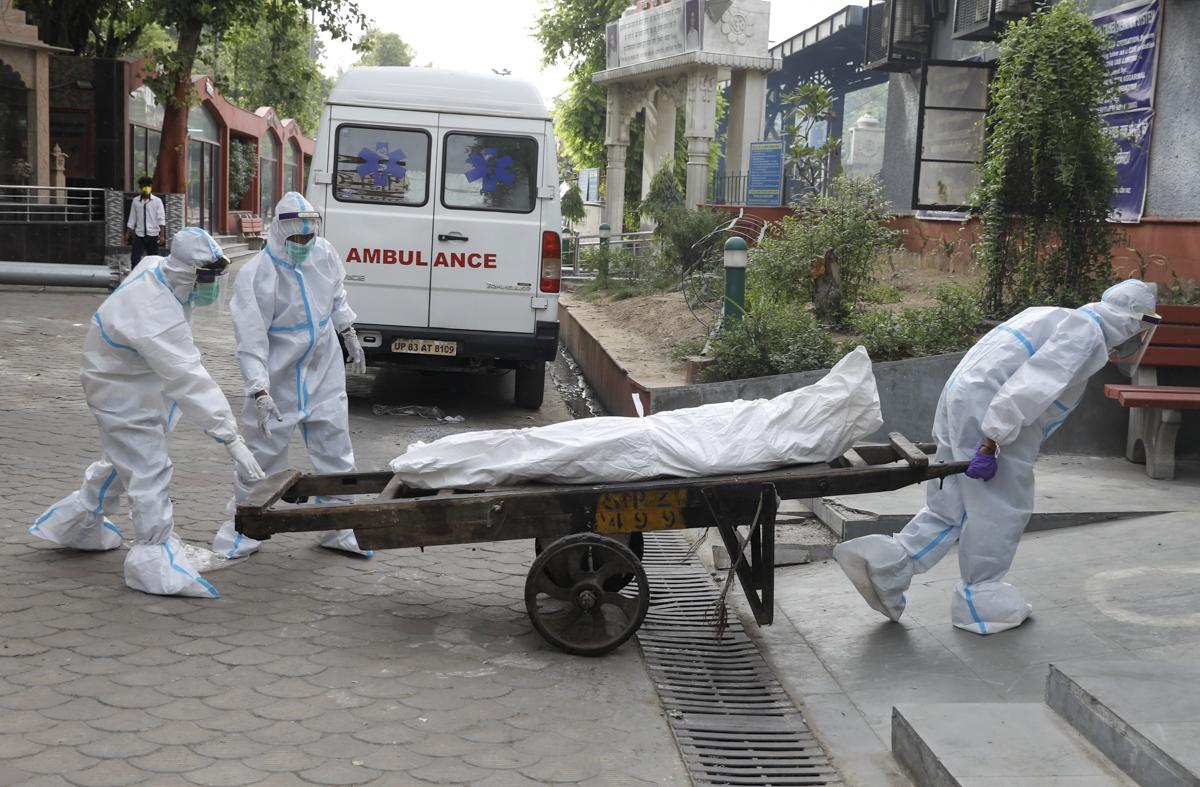 Health workers carry the body of a man at a crematorium in New Delhi. [Adnan Abidi/Reuters]