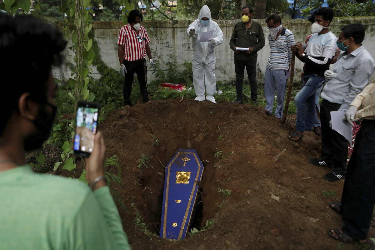 A priest prays over the coffin of a person who died from the COVID-19 disease during a funeral at a cemetery in Mumbai. [Francis Mascarenhas/Reuters]