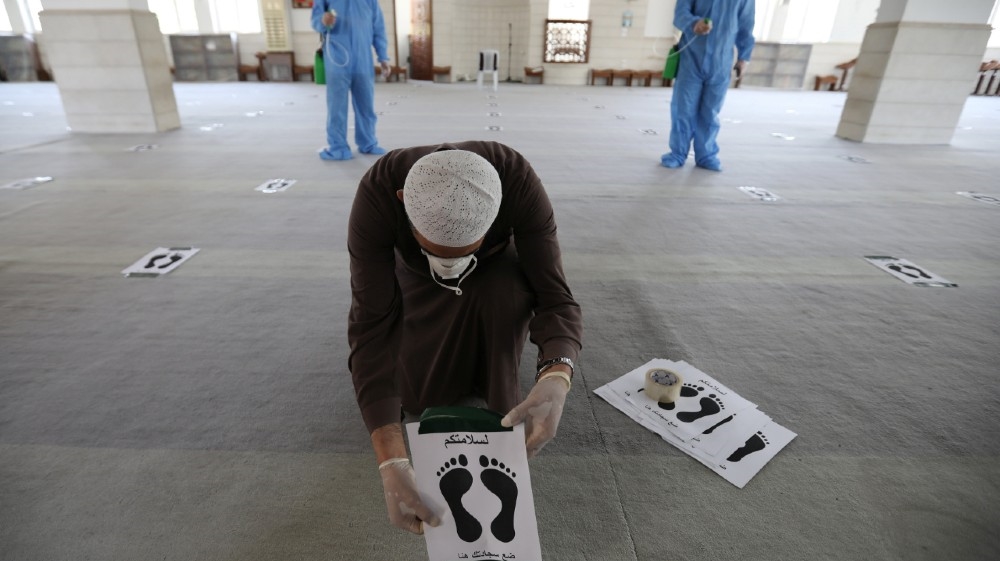 Imam of one the mosques puts foot print mats 