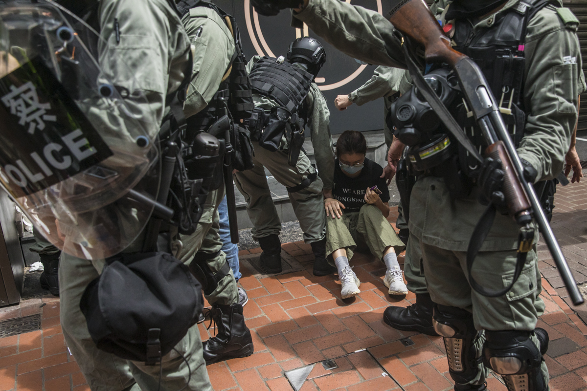 Riot police detain a woman as they clear protesters taking part in the rally against the new national security law. [Dale De La Rey/AFP]