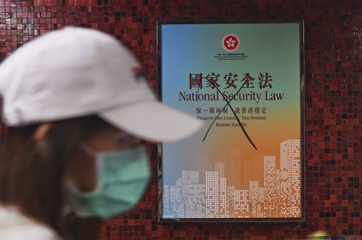 A commuter walks past a vandalised poster promoting the new national security law, in a subway station in Hong Kong. [Miguel Candela/EPA]