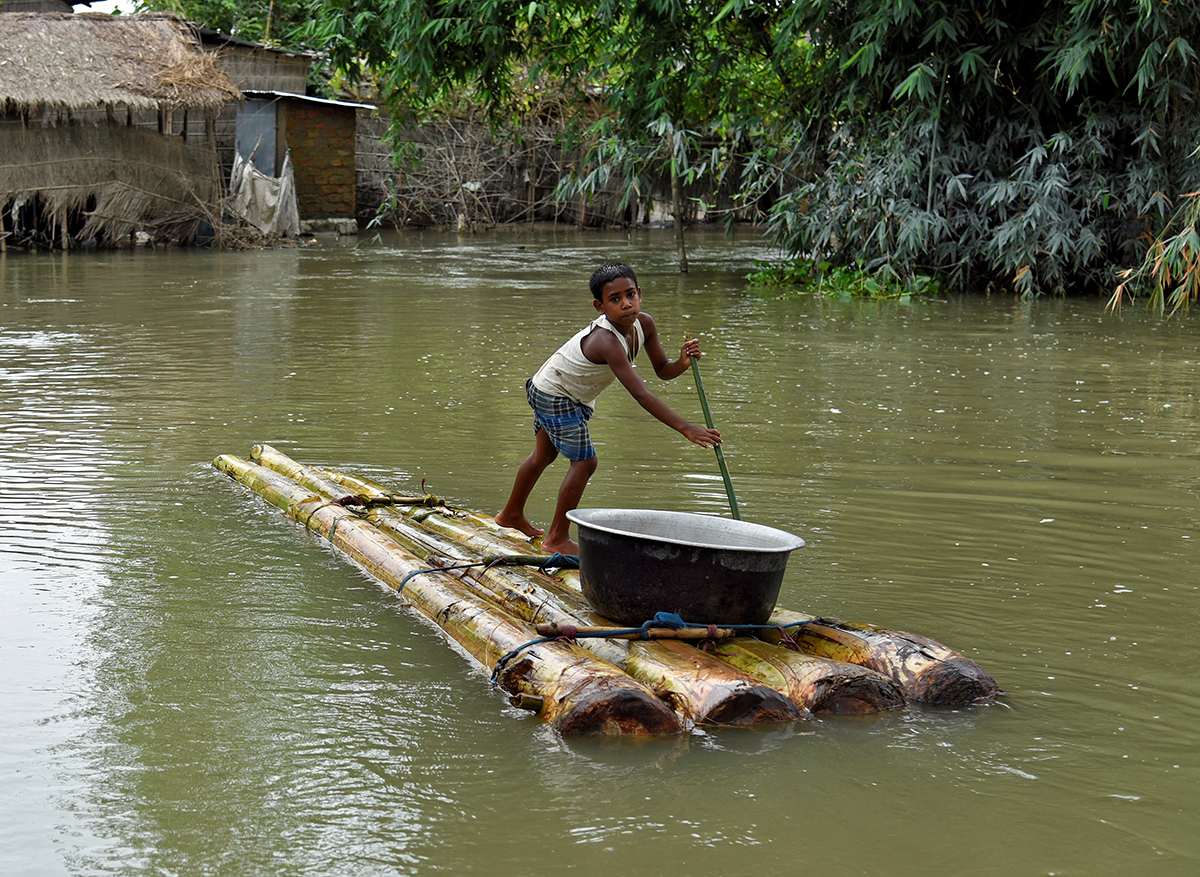 Një djalë në një udhëtim të paramenduar bën rrugën e tij përmes një zone të përmbytur në Assam, Indi.  Shumë fshatarë, shtëpitë e të cilëve nuk ishin zhytur plotësisht thanë se preferuan të qëndronin me gjërat e tyre përkundër kushteve të vështira.  [David Talukdar / Reuters]
