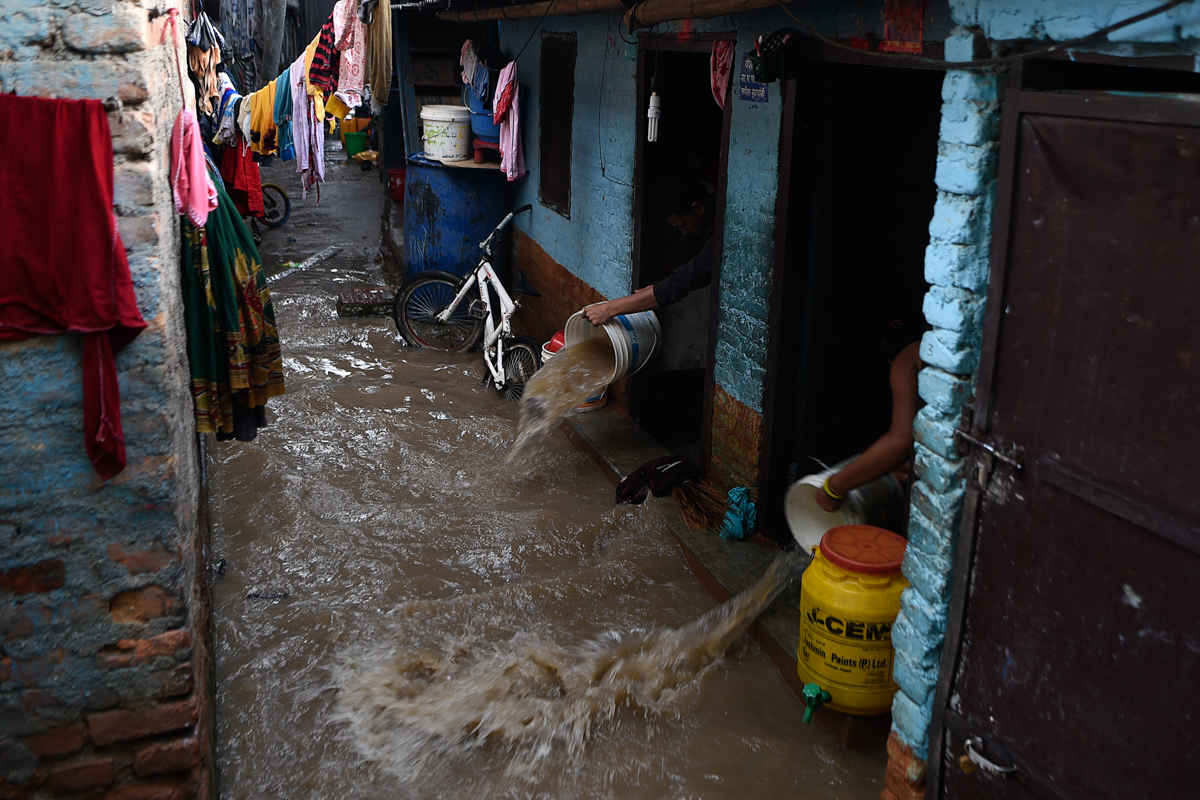 Banorët përdorin kova për të larguar ujin që rrjedh në shtëpinë e tyre pasi lumi Bagmati në Nepal shpërtheu brigjet e tij.  Qeveria ka lëshuar një paralajmërim të ri për rritjen e niveleve të lumenjve për tre ditët e ardhshme.  [Matematika Prakash / AFP]