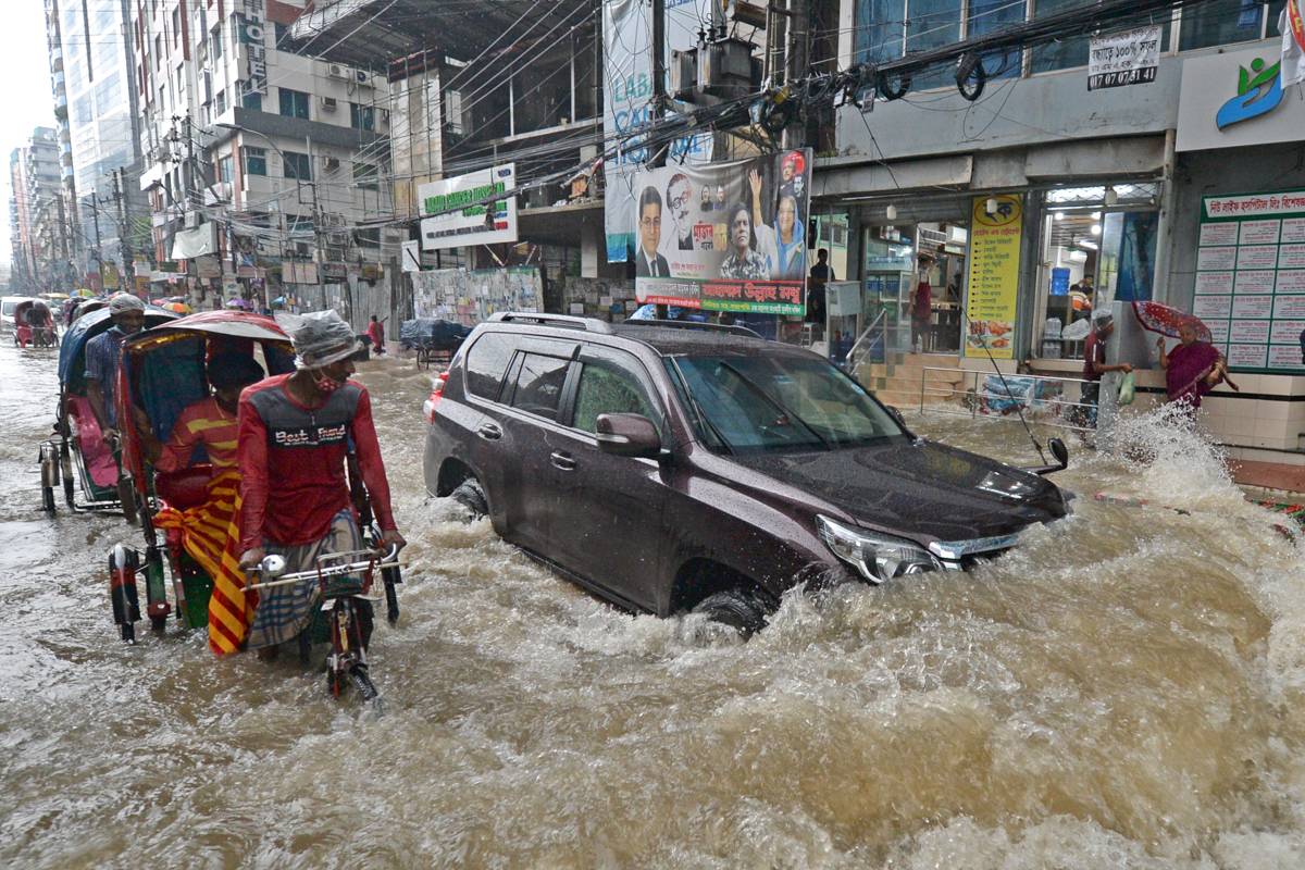Tregtarët kalojnë nëpër një rrugë pa ujë pas një rrëzimi të rëndë në Dhaka.  Gati një e treta e Bangladeshit tashmë është përmbytur, me parashikime për përmbytje më të mëdha në ditët e ardhshme.  [Munir Uz zaman / AFP]