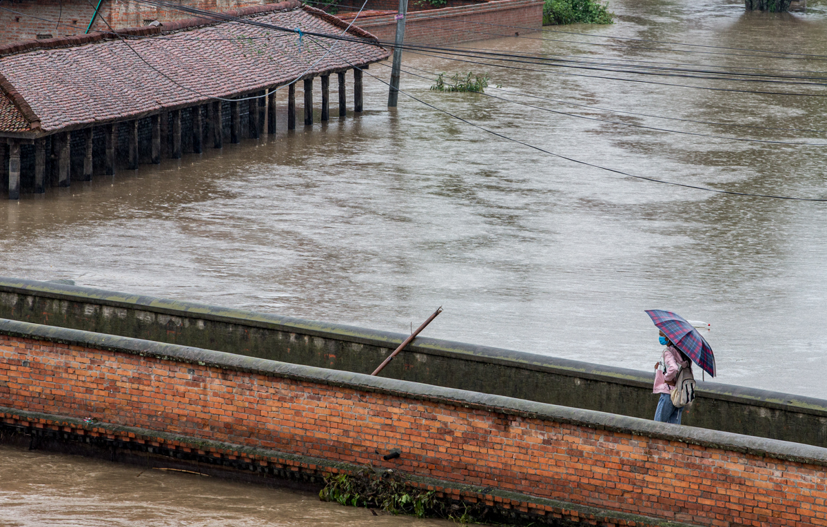 Një vajzë e re ecën nën një ombrellë ndërsa reshjet e mëdha përmbytin Bhaktapur të Nepalit.  IFRC tha se përmbytja dhe rrëshqitjet e dheut tashmë kanë vrarë pothuajse 110 njerëz në vend.  [Narendra Shrestha / EPA]
