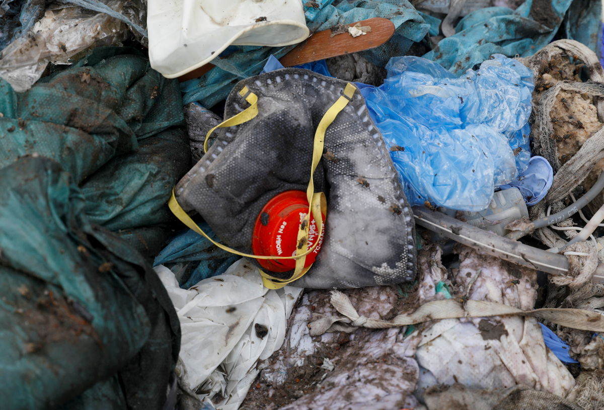 A discarded N95 protective face mask lies amongst other disposed medical waste. [Adnan Abidi/Reuters]