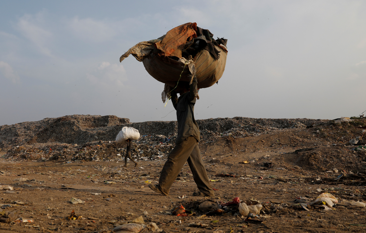 Mansoor Khan carries a sack of recyclable material. The $5 daily earnings enable their three children to go to school, seeking a future better than the livelihoods their parents have been able to eke out. [Adnan Abidi/Reuters]