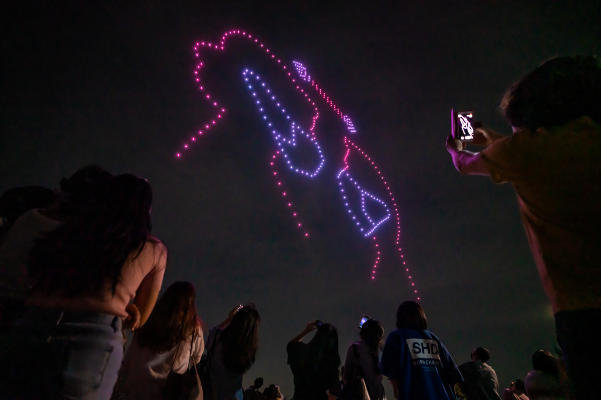 People taking photos of the drone display above the Han River in Seoul. [South Korea's Ministry of Land, Infrastructure and Transport/Handout via AFP]