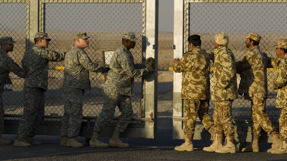 Kuwaiti and U.S. soldiers close the border gate after the last vehicle crossed into Kuwait during the US miltary's withdrawal from Iraq