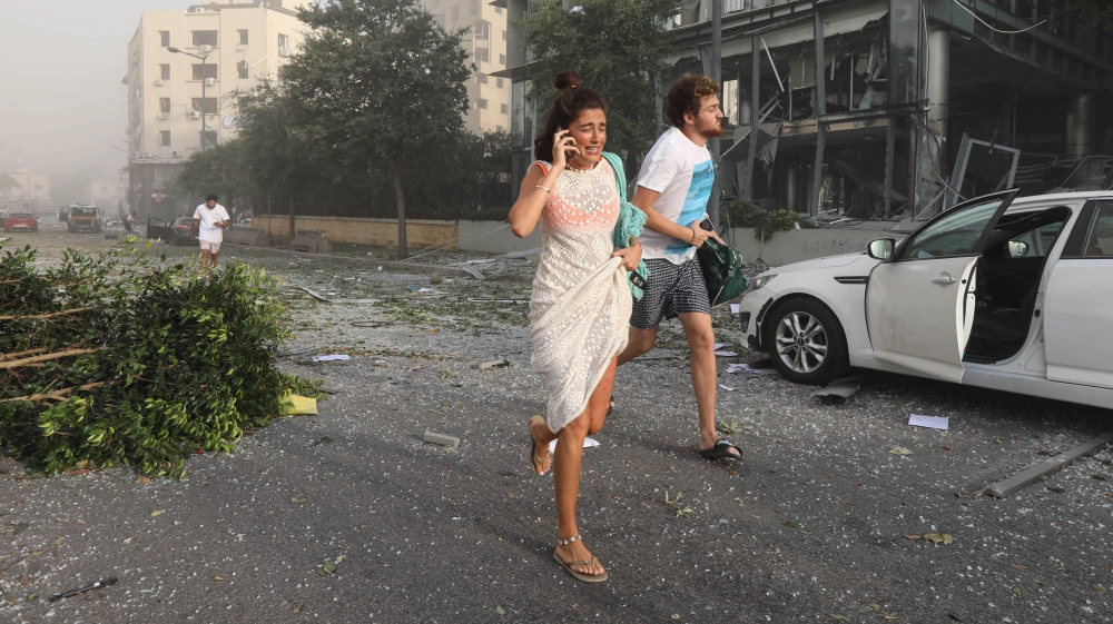People run for cover following an explosion in Beirut's port area