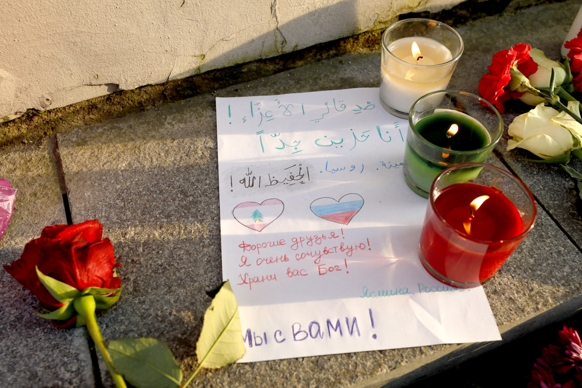 Flowers and candles brought to the Lebanese Embassy in Moscow to commemorate victims of the explosion in the port area of Beirut. A note reads: 'Dear friends! Our deepest condolences! God save you!' [Mikhail Japaridze\TASS via Getty Images]