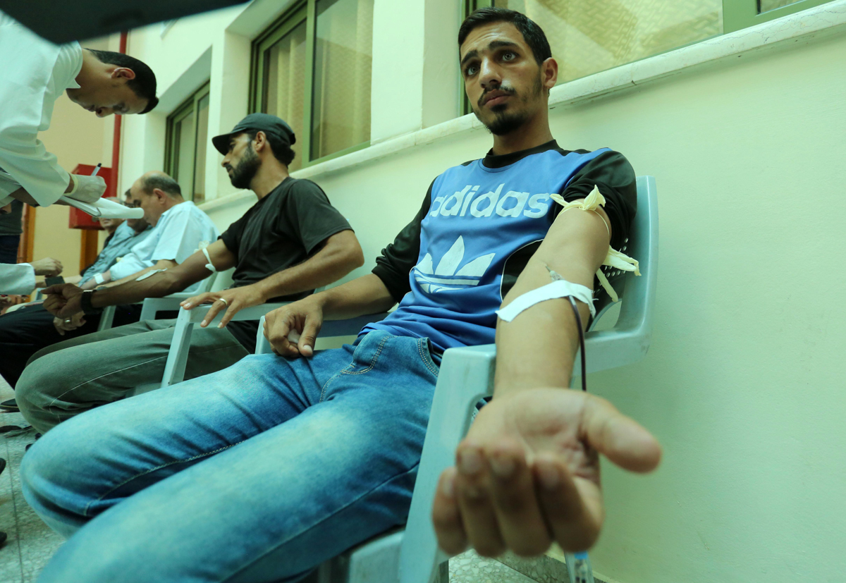 Palestinians donate blood in the Gaza Strip during a public blood donation campaign for the Lebanese community. [Majdi Fathi/NurPhoto via Getty Images]