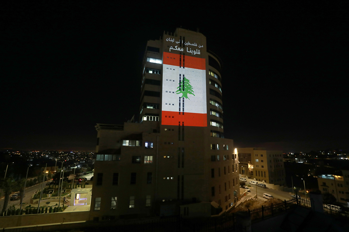 The Palestinian Broadcasting Corporation building is illuminated with the colours of the Lebanese flag as a sign of solidarity with the victims of the Beirut explosion, in Ramallah, occupied West Bank. [Issam Rimawi/Anadolu]