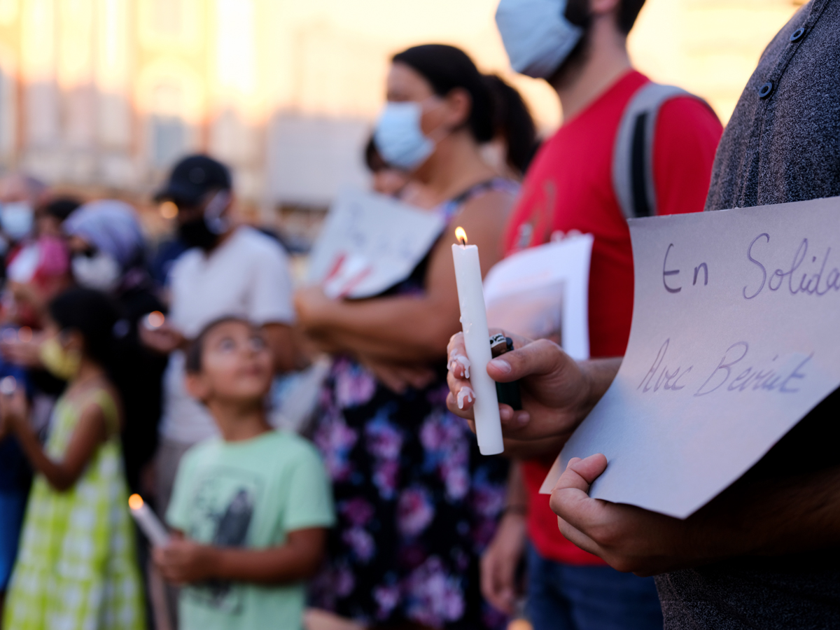 A man holds a 'Solidarity with Beirut' sign and a candle in Toulouse, France, during a gathering to pay tribute to the Lebanese people. [Remy Gabalda/AFP]